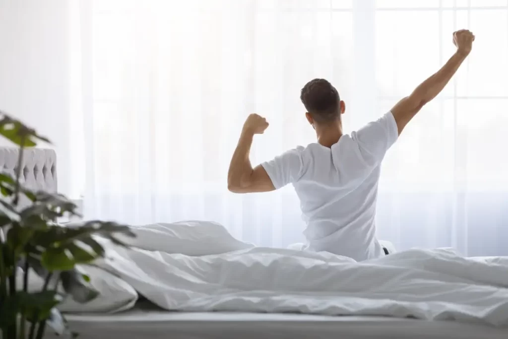 Une personne qui s'étire dans son lit le matin